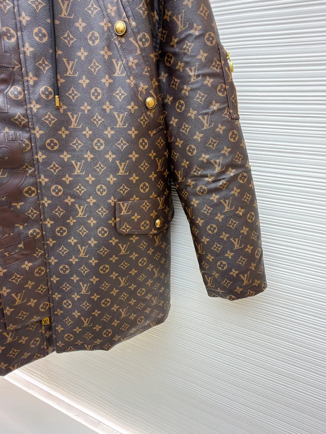 LOUIS VUITTON letter print hooded jacket ●Original version: Purchased and developed for 69999 ●Item number: 1681985-E40 ●Fabric: cotton fabric ●Technology: printing production ●Color: brown ●Version: fitted version ●Weight: about 1810 grams ●Size: 46-48-50-52 ●Description: This printed jacket is made of embossed leather fabric with a dark brown base and is fully printed with the classic Monogram pattern. The embossing process gives the logo a three-dimensional texture. The edge of the hood is spliced ​​with a natural fur collar, and the brim is equipped with an adjustable drawstring (metal rope buckle) to enhance warmth and style. The placket is double-closed with a two-way metal zipper and brass snap buttons. The zipper puller and snap button are both engraved with the brand logo, which is thick and durable. The body is designed with multiple pockets, and the pockets are edged with the same material + metal snap buttons for reinforcement. The left sleeve is equipped with a hidden adjustment tab. The interior is filled with high-fill down cotton, and the stitching adopts diamond-shaped quilting technology to prevent the filling from shifting. The seams are edged with leather of the same color, and the overall wiring is precise, taking into account warmth retention and luxurious texture. The overall wiring is straight and delicate, the fabric is comfortable and soft, and the color is consistent without color difference. It can be matched with the same style to create a fashionable look and control various occasions. Customized accessories, complete with three standards, same style for men and women!